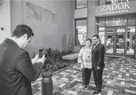  ?? Photos by Brett Coomer / Staff photograph­er ?? Gilad Zadok, left, takes a photo of his parents, Helene and Dror, outside the new Zadok Jewelers before opening day in Houston.