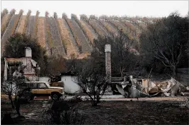  ?? JUSTIN SULLIVAN / GETTY IMAGES ?? A burned-out home sits next a vineyard after an out-of-control wildfire moved through the Sonoma, Calif., area on Monday. Tens of thousands of acres and dozens of homes and businesses have burned in Napa and Sonoma counties.