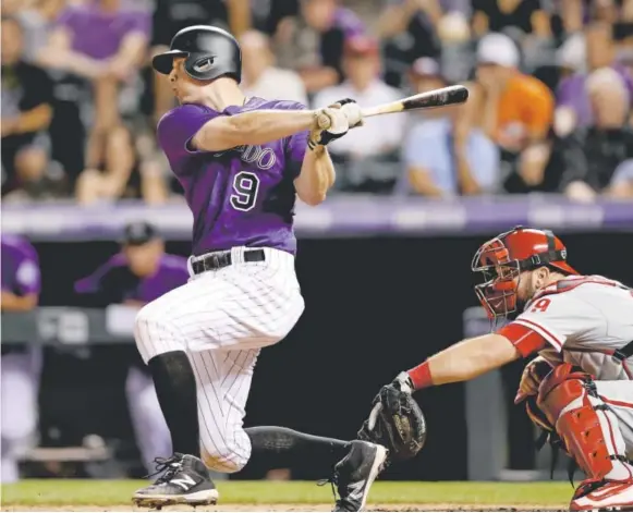  ?? Matthew Stockman, Getty Images ?? Colorado’s DJ LeMahieu hits an RBI single in the eighth inning against Philadelph­ia at Coors Field on Friday night, putting the Rockies up 4-3.