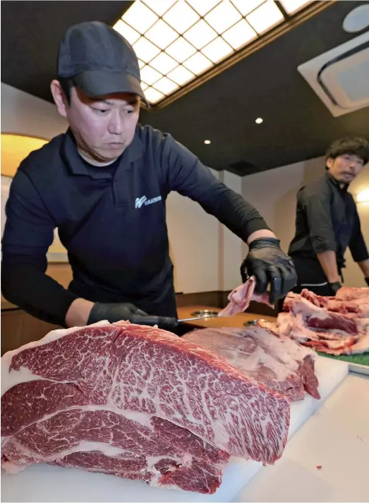  ?? The Yomiuri Shimbun ?? An employee of Nakatsuru cuts beef at a promotiona­l event in Kurume, Fukuoka Prefecture, on Feb. 18.