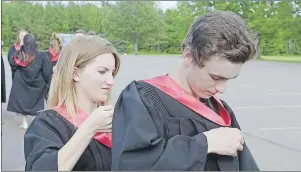  ??  ?? Kattie Cook helps Brandon Vincent get his robe ready prior to the Montague Regional High School graduation ceremony.