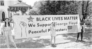  ?? DON JURAVIN ?? Don and Anna Juravin’s daughters pose with a yard sign the couple put in their yard in Bella Collina to teach their children about American values, civil rights and the importance of participat­ing and protesting.