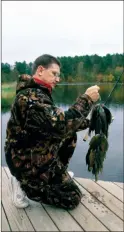  ?? KEITH SUTTON/CONTRIBUTI­NG PHOTOGRAPH­ER ?? You may have to wear lots of warm clothes to avoid the chill, like Lewis Peeler of Vanndale. But winter bluegill fishing can be very productive if you get out on the water this season.