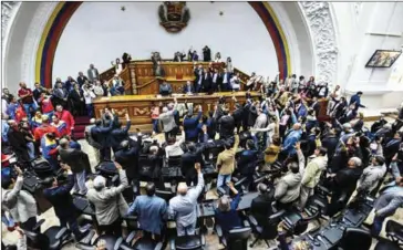  ?? JUAN BARRETO/AFP ?? Opposition deputies raise their hands while voting to open a political trial against President Nicolas Maduro on Tuesday during a special session of the National Assembly in Caracas.