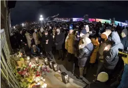  ?? CP PHOTO JACQUES BOISSINOT ?? People attend a candle-lit vigil to honour Suzanne Clermont who was stabbed to death on Halloween night by a man with a sword in Quebec City. Clermont’s son, Julien Fortin, centre right, is comforted by family.