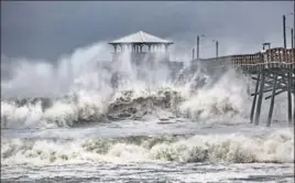 ?? AP ?? n Waves slam a pier at Atlantic Beach, North Carolina, on Thursday.