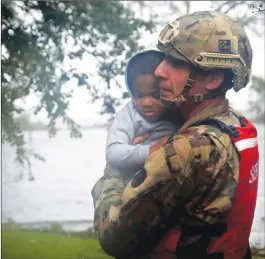  ?? Associated Press photo ?? Rescue team member Sgt. Nick Muhar, from the North Carolina National Guard 1/120th battalion, evacuates a young child as the rising floodwater­s from Hurricane Florence threatens his home in New Bern, N.C., on Friday.