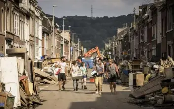  ?? Valentin Bianchi/Associated Press ?? Residents carry household belongings as they walk in a residentia­l street in Pepinster, Belgium, on Monday. People in several provinces continued to clean up after severe flooding.