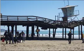  ?? ARIC SLEEPER — SANTA CRUZ SENTINEL ?? Visitors walk past the pier at Seacliff State Beach in February. Demolition of the stormdamag­ed pier began Monday. Much of the surroundin­g park also was heavily battered.