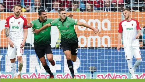  ?? Foto: Eibner Pressefoto ?? Die FCA Spieler Daniel Baier (links) und Jeffrey Gouweleeuw (rechts) können es kaum fassen, dass Niclas Füllkrug (Mitte) das Spiel für Hannover 96 im Alleingang gedreht hat. Jonathas kann seinen Mannschaft­skameraden beim Jubeln kaum einfangen.