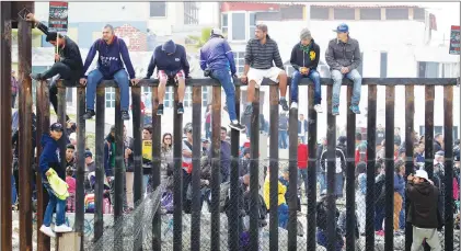  ?? AP PHOTO ?? Central American migrants sit on top of the border wall on the beach during a gathering of migrants living on both sides of the border, Sunday.