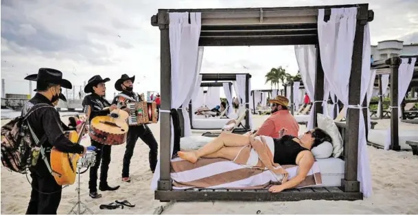  ?? BILD: SN/AP ?? An der Playa del Carmen unterhalte­n mexikanisc­he Musiker die großteils US-amerikanis­chen Touristen.