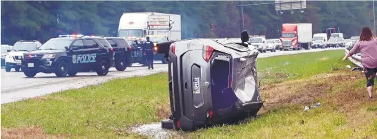  ?? JEFFREY F. BILL/BALTIMORE SUN MEDIA ?? The driver of an SUV walks around her vehicle in the median after a single-car crash on Interstate 97 north in Millersvil­le. Heavy rainstorms came through the area Monday afternoon.