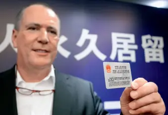 ??  ?? Le 16 juin 2017, un étranger présente sa carte de résidence permanente en Chine, à Hangzhou.