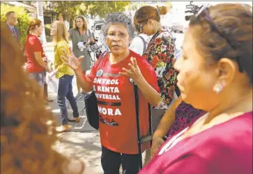  ?? Al Seib Los Angeles Times ?? ALEJANDRA SANTIAGO with the Los Angeles Tenants Union speaks with residents outside their bungalows on Grand View Street near MacArthur Park. A developer wants to build affordable housing on the site.