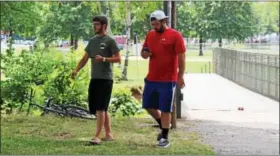  ??  ?? Two people walk at Memorial Park in Pottstown while playing Pokemon Go. The game app has become extremely popular since its launch.