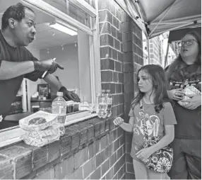  ?? PHOTOS BY ARIEL COBBERT/THE COMMERCIAL APPEAL ?? Volunteer Brad Watkins hands out grab-and-go meals through a window at Caritas Community Center and Cafe in Binghampto­n last Tuesday. Caritas Community Center and Cafe offers free daily meals to out-of-work Memphians.