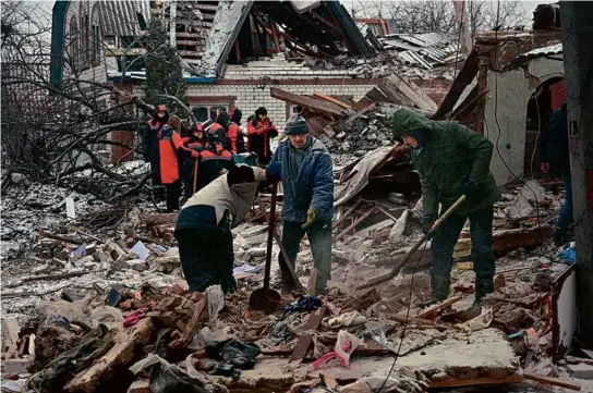  ?? SERGEY BOBOK/AFP VIA GETTY IMAGES ?? Rescuers and residents cleared debris following Russian strikes in Zmiiv, Kharkiv region, Monday.