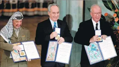  ?? JERRY LAMPEN / REUTERS ?? Shimon Peres (center), shows his Nobel Peace Prize flanked by co-recipients Yasser Arafat, the late chairman of the Palestine Liberation Organizati­on, and then-Israeli prime minister Yitzhak Rabin, in Oslo, Norway, in 1994. Peres was Israel’s foreign...