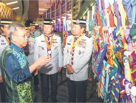  ?? – Photo by Chimon Upon ?? Dr Sim takes a look at the various scout scarves on display in conjunctio­n with the anniversar­y celebratio­n. Looking on are Mawan and Scout Malaysia chief Major General (Rtd) Prof Dato Mohd Zin Bidin (right).