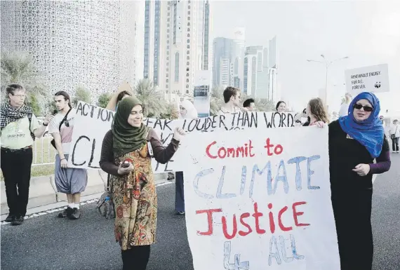  ??  ?? ACTIVISTAS en favor de medidas para proteger el clima se manifiesta­n en el marco de la cumbre que se celebra en Doha, Qatar.