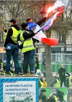 ??  ?? Demonstrat­ors wave a French national flag and a flare as they gather in the place de la Bastille, in Paris during anti-government demonstrat­ion called by the Yellow Vest ‘Gilets Jaunes’ movement. — AFP photos