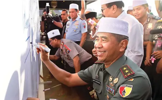  ?? HANUNG HAMBARA/JAWA POS ?? SATU TEKAD: Dari kiri, Kapolda Jatim Irjen Pol Machfud Arifin, Gubernur Soekarwo, dan Pangdam V/ Brawijaya Mayjen TNI Arif Rahman menandatan­gani spanduk berisi kutukan terhadap aksi terorisme di lapangan Mapolda Jatim.