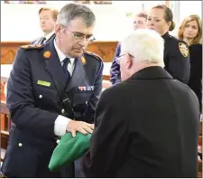  ??  ?? Garda Commission­er Drew Harris presents Marty Horkan the tricolour and the cap and gloves of his son Colm at the end of the funeral Mass on Sunday.