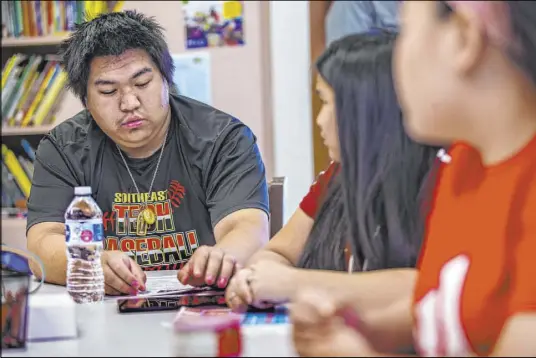  ?? L.E. Baskow Las Vegas Review-Journal @Left_Eye_Images ?? From left, siblings Mark, Jenna and Lena Lacksanamy­xay learn to operate a free Galaxy tablet June 22. The family was homeless for nearly a year before recently finding a home through the Southern Nevada Regional Housing Authority.