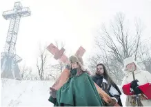  ??  ?? A man dressed as Paul de Chomedey de Maisonneuv­e, left, a founder of Montreal, carries a crucifix to commemorat­e the raising of the cross on Mount Royal in 1643.