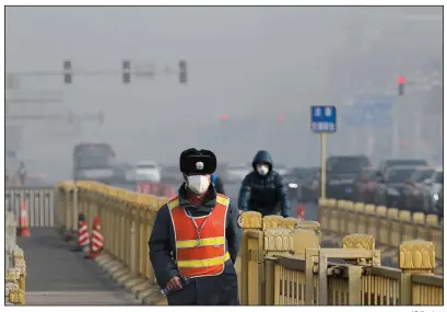  ?? AP file photo ?? A traffic officer wearing a mask patrols near Tiananmen Square in Beijing as smog blankets the Chinese capital in January. Antipollut­ion efforts have helped improve air quality in Beijing.