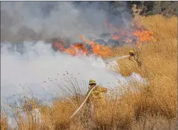  ?? Bobby Block/The Signal ?? Los Angeles County Fire Department personnel battle flames from the Elsmere Fire between Highway 14 and Sierra Highway in Newhall on Monday.