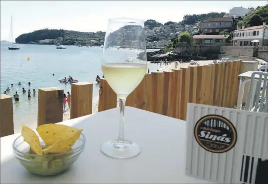  ?? JUANMA GARCÍA ?? Aperitivo de nachos con guacamole y copa de vino de Ribeiro, en una mesa del ‘Chiringuit­o de Sinás’ (Raxó), frente a la Ría de Pontevedra.