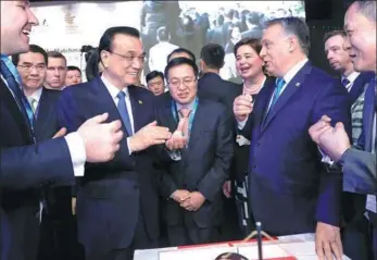  ?? JU PENG / XINHUA ?? Premier Li Keqiang and Hungarian Prime Minister Viktor Orban (center, right) talk with entreprene­urs after the opening of the seventh China and the Central and Eastern European Countries Economic and Trade Forum in Budapest, Hungary, on Monday.