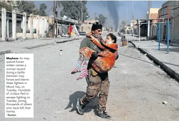  ??  ?? Mayhem: An Iraqi special forces soldier carries a woman injured during a battle between Iraqi forces and Islamic State fighters in Mosul, Iraq, on Tuesday. Hundreds of civilians fled to escape fighting on Tuesday, joining thousands of others who have...