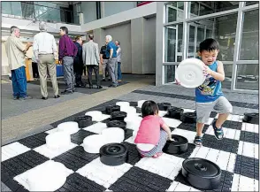  ?? NWA Democrat-Gazette/FLIP PUTTHOFF ?? Children play with a jumbo checkers game Tuesday as guests gather for the announceme­nt about new Allegiant Air flights between Northwest Arkansas Regional Airport and Phoenix.