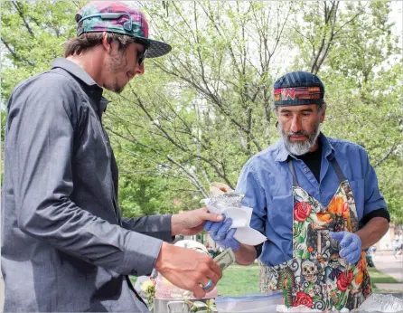  ?? PHOTOS BY ADRIANA SANCHEZ/FOR THE NEW MEXICAN ?? Austin Girard, left, a regular at Balam’s Burritos, pays for a burrito Monday on the Plaza. Also seen is vendor Balam Lemus.