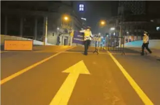  ?? ?? Police officers remove barricades on the Sichuan Road Bridge late on Saturday night. The bridge across the Suzhou Creek is the border between Shanghai’s Huangpu and Hongkou districts.
— Dai Qian