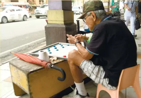  ?? (SUN.STAR FOTO/ALLAN CUIZON) ?? STREET TECHNIQUES. An old man waits for an opponent as he studies some techniques to win his game.