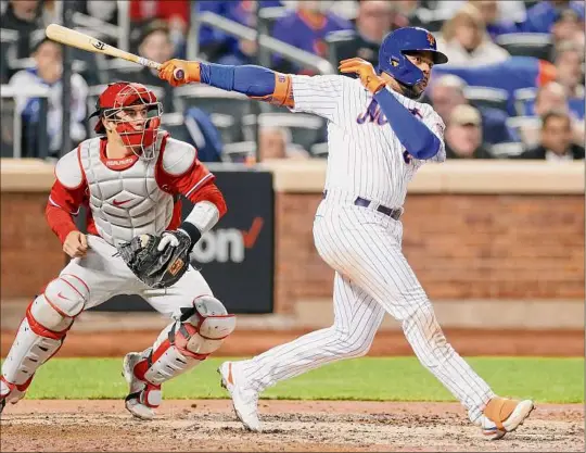  ?? Sarah Stier / Getty Images ?? Dominic Smith of the Mets hits an RBI double as the Phillies’ J.T. Realmuto watches. Smith finished 4-for-4 in New York’s 10-6 victory.