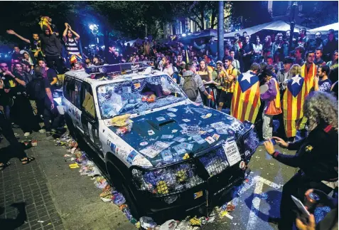  ??  ?? A Guardia Civil patrol car is left abandoned as pro-independen­ce demonstrat­ors gather to protest outside the regional ministry of economy’s headquarte­rs in Barcelona yesterday