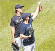  ?? Kathy Willens / Associated Press ?? New York Yankees starting pitcher Gerrit Cole, left, talks to relief pitcher Zack Britton about a grip during a baseball summer training camp workout on Sunday at Yankee Stadium in New York.