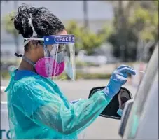  ?? Allen J. Schaben Los Angeles Times ?? MARITZA PEREZ, a registered nurse, administer­s a COVID-19 test to a motorist at AltaMed Health Services in Anaheim.