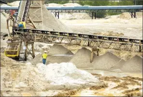  ?? AP/Houston Chronicle/BRETT COOMER ?? A worker sprays down piles of sand last month at the Superior Silica Sands mine in Kosse, Texas.