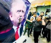  ?? (Mussa Qawasma/Reuters) ?? A PALESTINIA­N demonstrat­or throws a shoe at a poster depicting US President Donald Trump during a protest in Hebron earlier this year.