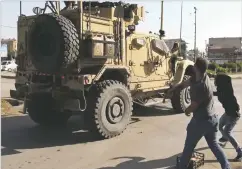  ?? ANHA VIA AP ?? In this frame grab from video provided by Hawar News, ANHA, the Kurdish news agency, residents angry over the U.S. withdrawal from Syria hurl potatoes Monday at American military vehicles in the town of Qamishli, in northern Syria.