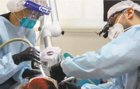  ?? Santiago Mejia / The Chronicle ?? Wearing an N95 mask and face shield, Liv Tammik (left) works alongside Lior Tamir at Bloom Dental Group in San Mateo.