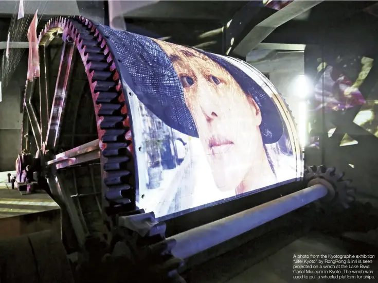  ?? ?? A photo from the Kyotograph­ie exhibition “Jifei Kyoto” by RongRong & inri is seen projected on a winch at the Lake Biwa Canal Museum in Kyoto. The winch was used to pull a wheeled platform for ships.