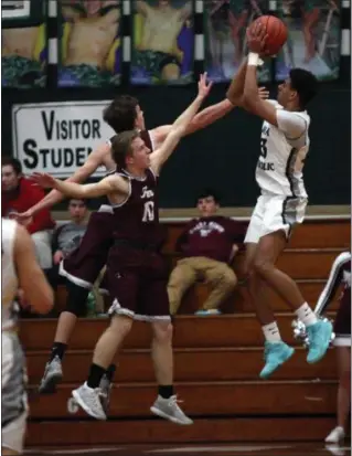  ?? RANDY MEYERS — FOR THE MORNING JOURNAL ?? Elyria Catholic’s Jarred Logan shoots over Connor O’ Toole and Luke Coyne of Rocky River during the second quarter at Elyria Catholic last year.