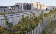  ?? KATHY WILLENS — THE ASSOCIATED PRESS ?? Five years after Superstorm Sandy, dune plantings border a broad concrete boardwalk separating residentia­l buildings, left, from the beach in Rockaway Beach in the Queens borough of New York on Thursday. The area, which was heavily damaged by storm...